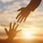 Silhouette of giving a helping hand, hope and support each other over sunset background.